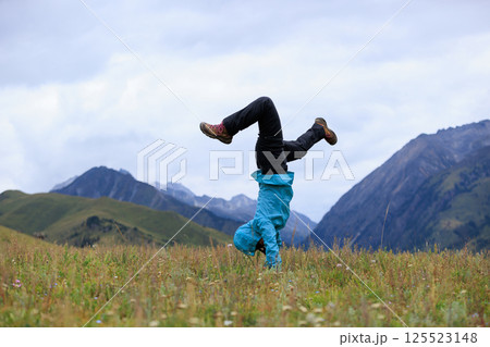 Woman hiker doing a handstand on high altitude mountain meadow 125523148