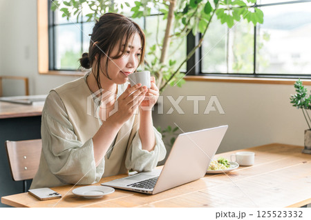 カフェで食事をしながらテレワークをする若いアジア人女性 125523332