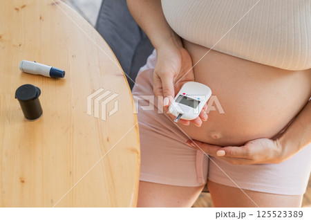 Pregnant woman doing home blood sugar test. Gestational diabetes.  125523389