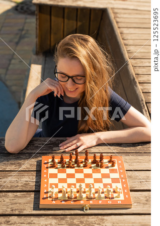 Caucasian woman playing chess outdoors. Caucasian woman playing chess outdoors. 125523695