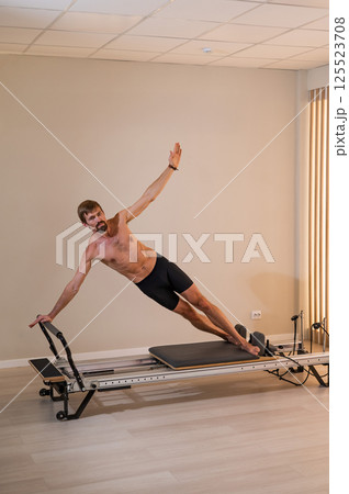 A man doing Pilates on a reformer. A man doing Pilates on a reformer. 125523708