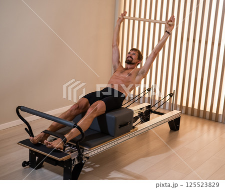 A man doing Pilates on a reformer. A man doing Pilates on a reformer. 125523829