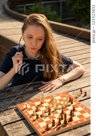 Caucasian woman playing chess outdoors. 125523832