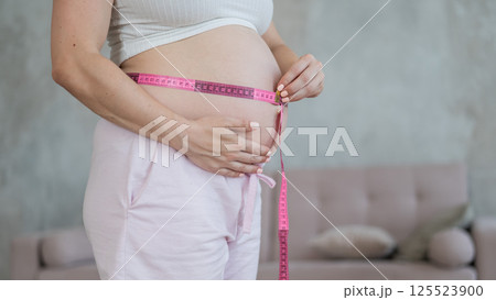Pregnant woman measuring her belly. Pregnant woman measuring her belly. 125523900