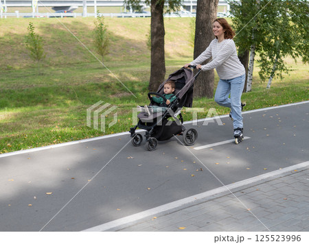 Caucasian woman roller skating with her toddler son in a stroller.  125523996
