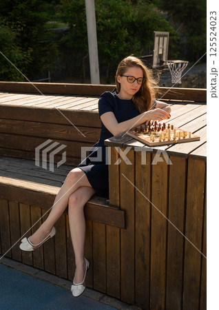Caucasian woman playing chess outdoors. Caucasian woman playing chess outdoors. 125524023