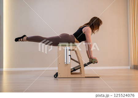 Asian woman doing pilates classic chair. Asian woman doing pilates classic chair. 125524076