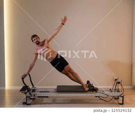 A man doing Pilates on a reformer. A man doing Pilates on a reformer. 125524132