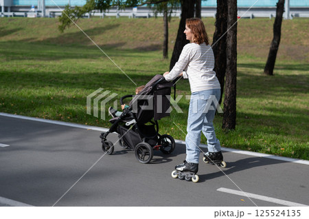Caucasian woman roller skating with her toddler son in a stroller.  125524135