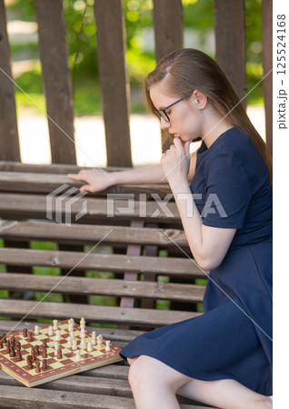 Caucasian woman playing chess outdoors. 125524168