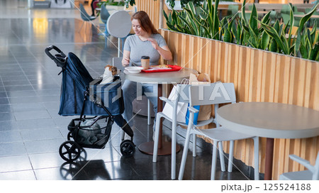Caucasian woman having lunch in a cafe with her Jack Russell terrier dog in a stroller.  125524188