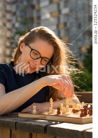 Caucasian woman playing chess outdoors. 125524234
