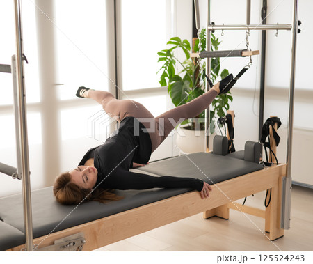 Woman doing Pilates on reformer. Woman doing Pilates on reformer. 125524243