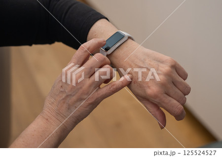 Elderly Caucasian woman looking at smart watch. Close-up of hands.  125524527