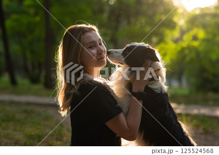 Young Caucasian woman hugging her border collie dog while walking in the park. Young Caucasian woman hugging her border collie dog while walking in the park. 125524568