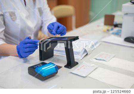 A narcologist tests urine for drugs using an electronic device.  125524660
