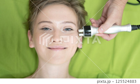 Top view of Caucasian woman undergoing radio wave RF lifting procedure in beauty salon.  125524883