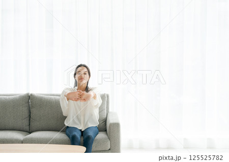 ソファに座ってストレッチをする女性 ソファに座ってストレッチをする女性 125525782