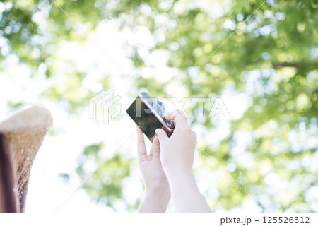 公園でカメラを構える女性の手元 125526312