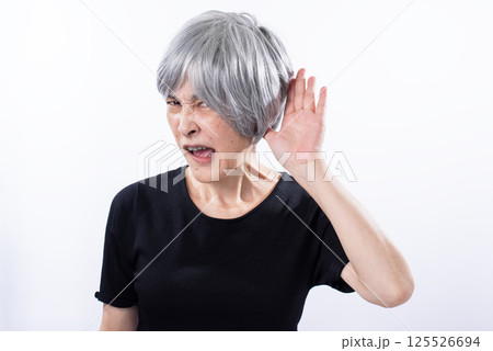 とても嫌そうに聞き耳を立てるシニア女性 125526694