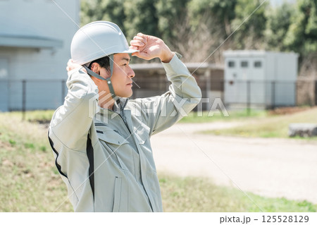 作業着姿のヘルメットを被った作業員のアジア人男性 125528129