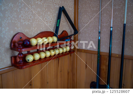 Home billiard setup with white balls, red cue ball, triangle rack, and cues neatly arranged. Concept of indoor recreation and personal hobby space Home billiard setup with white balls, red cue ball, triangle rack, and cues neatly arranged. Concept of indoor recreation and personal hobby space 125528607