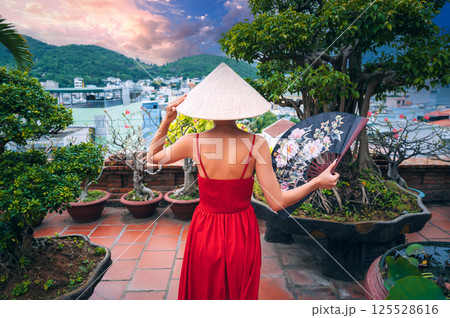 back of beautiful female tourist traveler in Vietnamese non la hat and fan is traveling in Vietnam in Asia 125528616