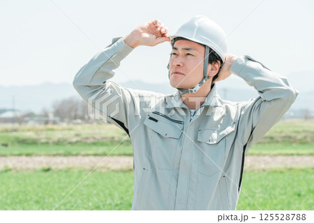 田舎の田んぼに立つ作業着姿のミドル世代の作業員・職人・現場監督 125528788