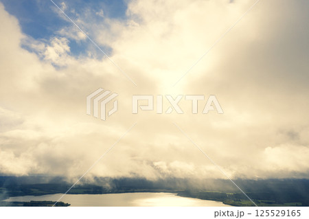 Aerial view clouds over the forest and lake. View from drone. Aerial top view cloudscape. Texture of clouds. View green forest from above covered with white clouds 125529165