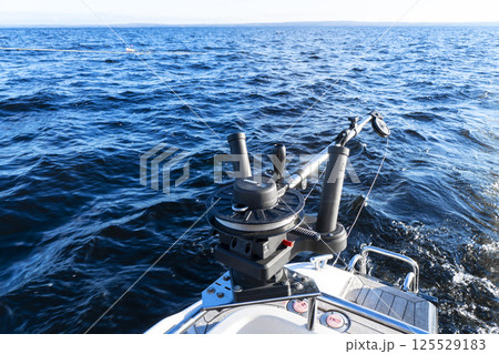 Fishing equipment on boat. Downrigger boat gear for trolling. Fishing boat with down rigger trolling in blue ocean. Fisherman boat in the sea Fishing equipment on boat. Downrigger boat gear for trolling. Fishing boat with down rigger trolling in blue ocean. Fisherman boat in the sea 125529183