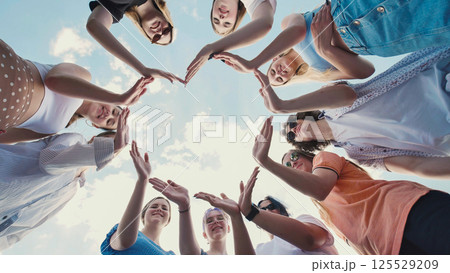 School friends united in teamwork, forming a star shape against a cloudy sky 125529209