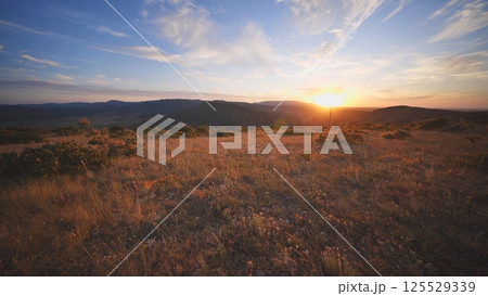 Sunset illuminating dry Crimean steppe landscape with hills and meadows 125529339