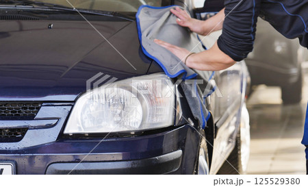Car wash employee drying vehicle with microfiber cloth 125529380