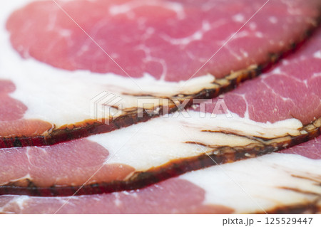 Top view of smoked pork salami chorizo sausages slices background. Raw smoked salami pattern 125529447
