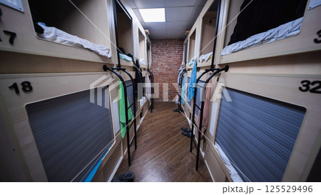 Rows of capsule beds in modern hostel dormitory offering comfortable and affordable accommodation 125529496