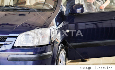Car wash worker cleaning vehicle with high pressure water jet 125530177