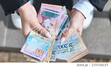 Woman clutching worthless venezuelan bolivar bills, revealing hyperinflation's devastating economic impact Woman clutching worthless venezuelan bolivar bills, revealing hyperinflation's devastating economic impact 125530225