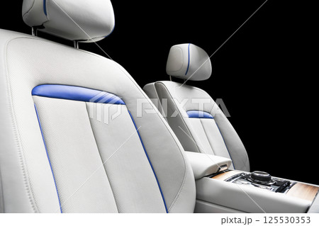 Modern luxury car white leather interior with natural wood panel. Part of leather car seat details with stitching. Interior of prestige modern car. White perforated leather. Car detailing. Car inside 125530353