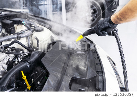 Car detailing. Car washing cleaning engine. Cleaning car using hot steam. Hot Steam engine washing. Soft lighting. Car washman worker cleaning vehicle. 125530357