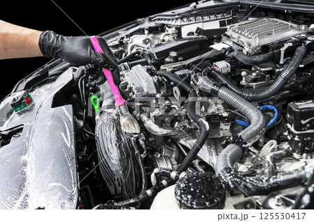 A man cleaning car engine with shampoo and brush. Car detailing or valeting concept. Selective focus. Car detailing. Cleaning with sponge. Worker cleaning. Car wash concept solution to clean 125530417