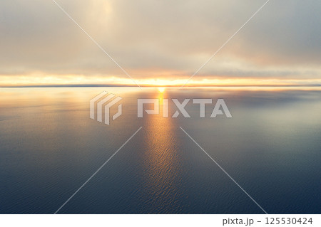 Aerial view of a sunset sky background. Aerial Dramatic gold sunset sky with evening sky clouds over the sea. Sky landscape. Aerial photography. 125530424
