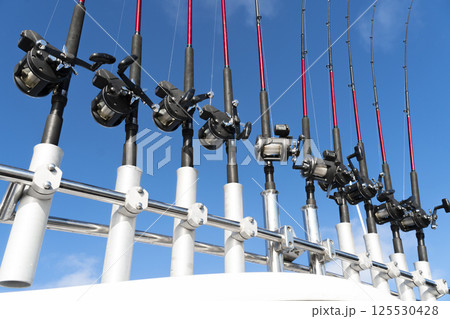 Fishing trolling boat rods in rod holder. Big game fishing. Fishing reels and rods pattern on boat. Sea fishing rods and reels in a row 125530428