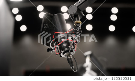 Microphone in studio. Professional studio microphone with a pop filter is suspended boom arm and studio lights. Set up mic for podcast voice over or recording high quality sound audio in a controlled. 125530531