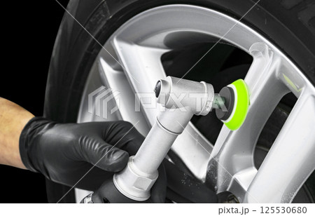 Car polish wax worker hands polishing car wheel. Buffing and polishing car disc. Car detailing. Man holds a polisher in the hand and polishes the car.in the hand and polishes the car. Tools for 125530680