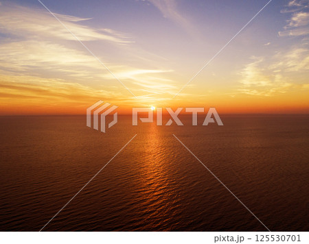 Aerial view of a Sunset sky background. Aerial Dramatic gold sunset sky with evening sky clouds over the sea. Stunning sky clouds in the sunset. Sky landscape. Aerial photography. 125530701