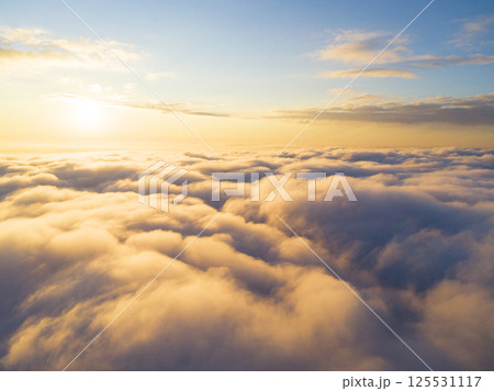 Aerial view White clouds in blue sky. Top view. View from drone. Aerial bird's eye view. Aerial top view cloudscape. Texture of clouds. View from above. Sunrise or sunset over clouds 125531117