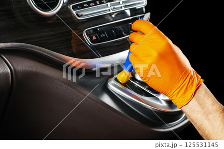 A man cleaning car with cloth and brush. Car detailing. Selective focus. Car detailing. Cleaning with brush. Worker cleaning. Brush and cleaning solution to clean. 125531145