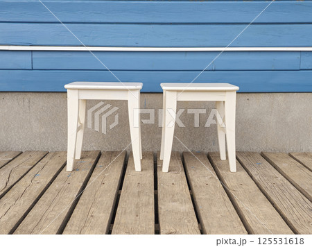 Two white stool against a blue home wall. 125531618