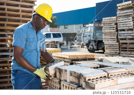 Man carrying hollow concrete blocks outdoors Man carrying hollow concrete blocks outdoors 125531710