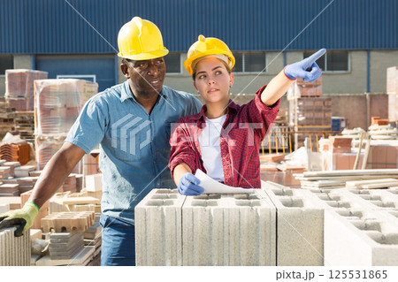 Builders talking in construction material storage Builders talking in construction material storage 125531865